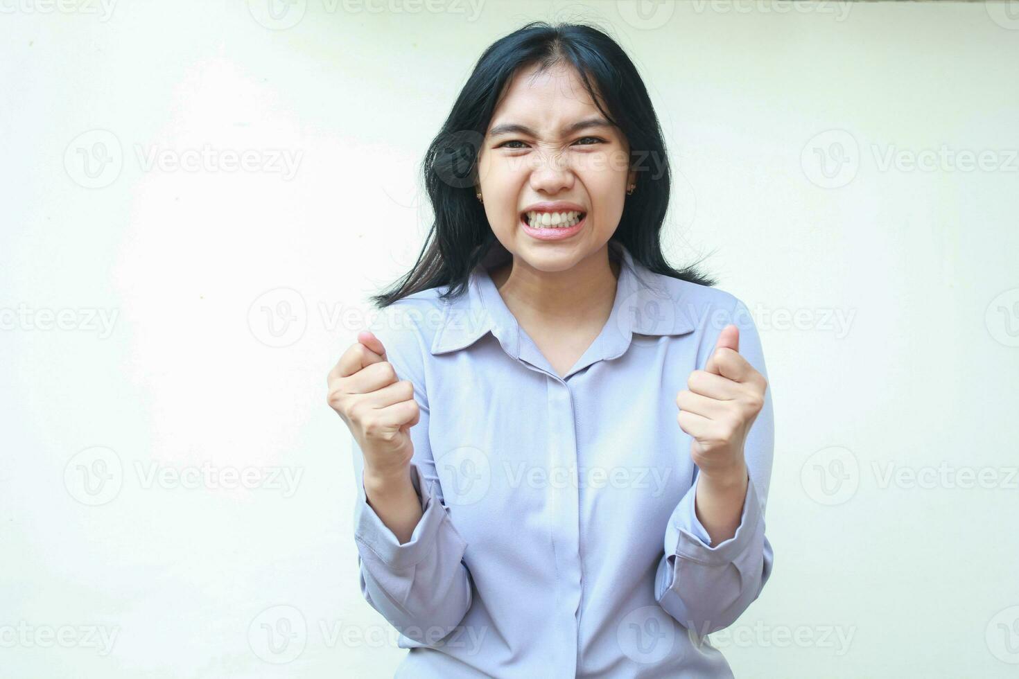 angry asian young business woman raising fist and grabbing hand wear formal shirt, frowning and aggresive face expression isolated on white, looking to camera photo