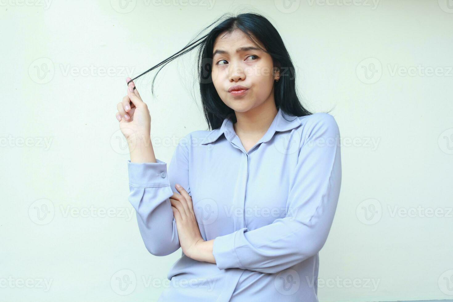 thoughtful asian beautiful woman thinking seriously and pulling her dark hair looking away day dreaming dressed in formal purple suit, isolated in white background photo