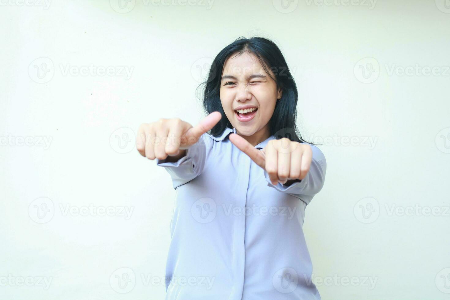 studio shot of confident excited asian young business woman giving two thumbs up and blink eye to camera satisfied, approval gesture and yes pose of female wearing formal shirt isolated in white photo