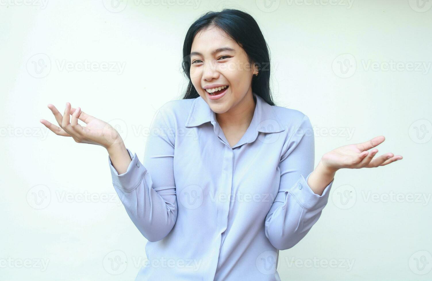 beautiful hesitant asian business woman smiling to camera clueless and spreads palm sideways wearing formal shirt isolated on white background photo