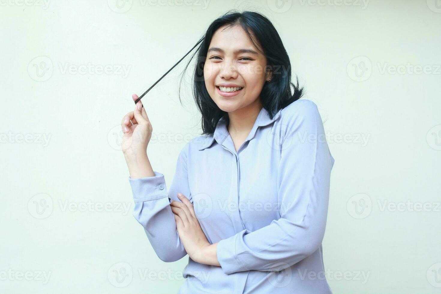 happy beautiful asian young business woman smiling excited to camera with holding hair and folded arm, enjoy and relaxing female office worker dressed in formal shirt isolated on white background photo