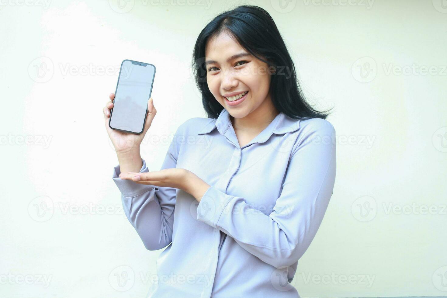 pretty asian young business woman dressed in formal shirt showing white screen of mobile phone with smiling face, mock up product advertising, isolated on white background photo