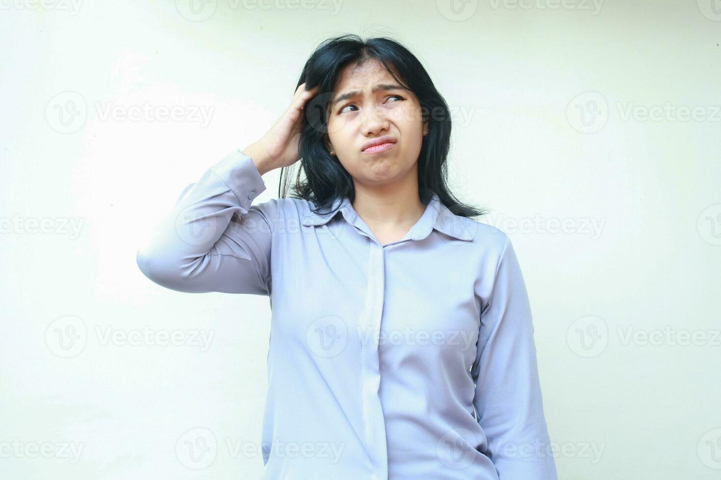 confuso asiático mujer mirando encima con curiosidad conmovedor su cabeza vestido en formal traje aislado en blanco antecedentes foto