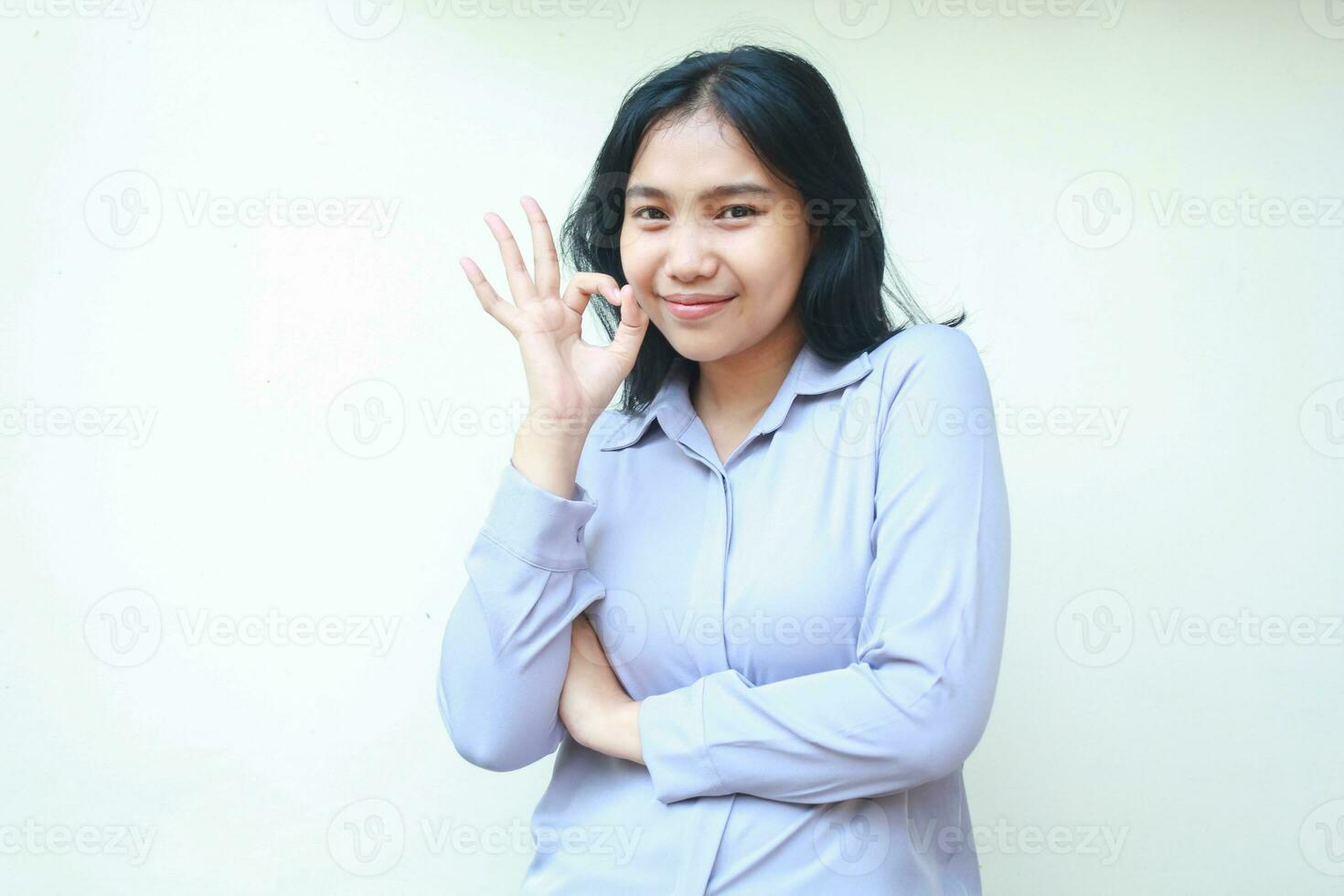 happy asian young business woman show ok sign perfection gesture look camera with confidence smile, folded arm female wear formal shirt isolated background photo