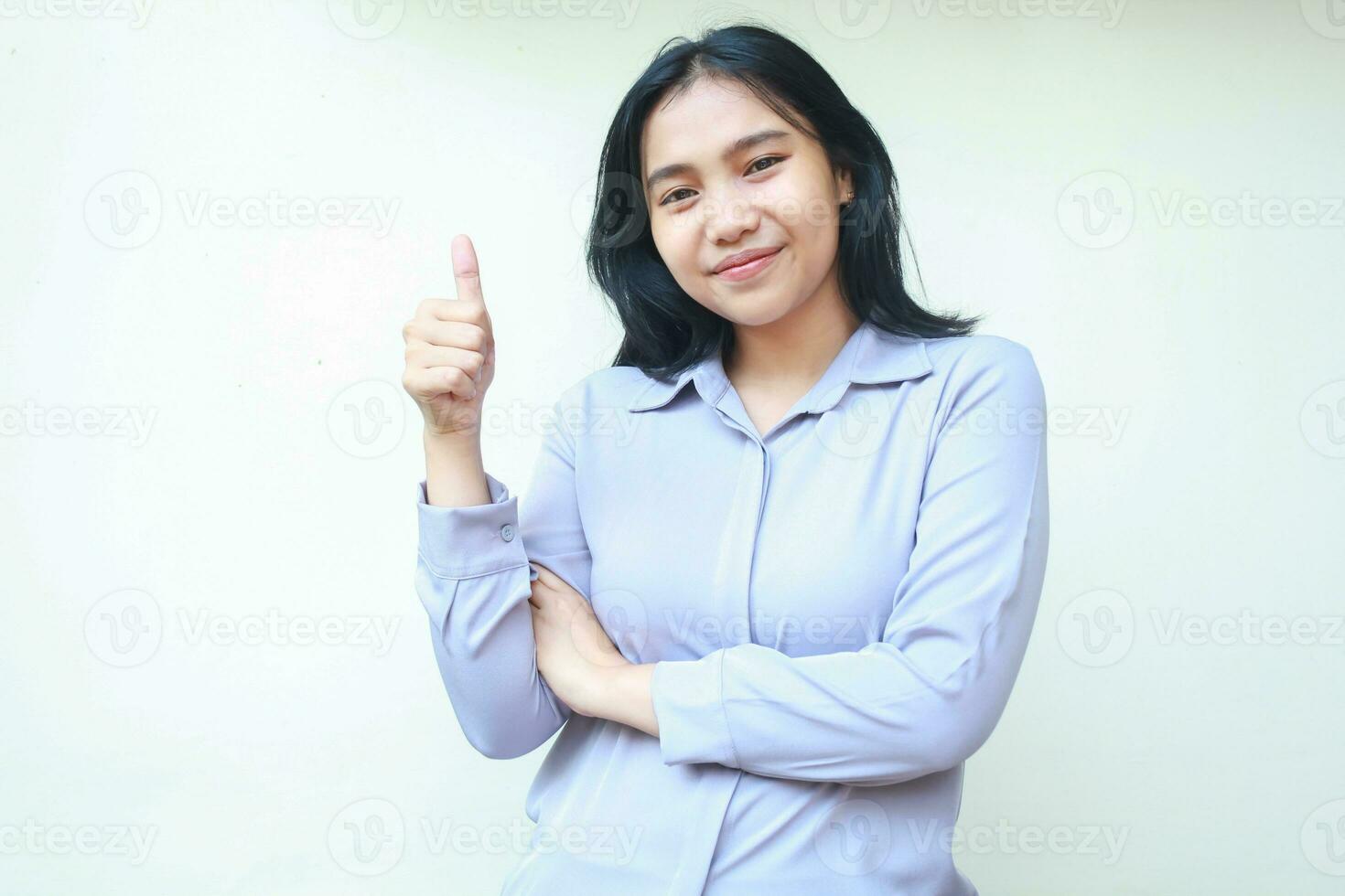 portrait of happy asian pretty young business woman giving thumbs up with folded arm look to camera satisfied, excellent gesture client, wear formal shirt isolated on white background photo