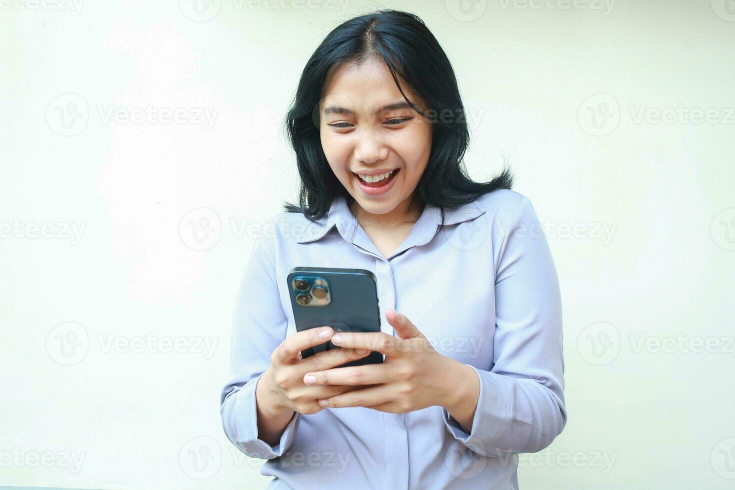 beautiful asian young business woman excited looking to smartphone hold on hand, texting and chatting female wear formal shirt isolated in white background, online lifestyle concept photo