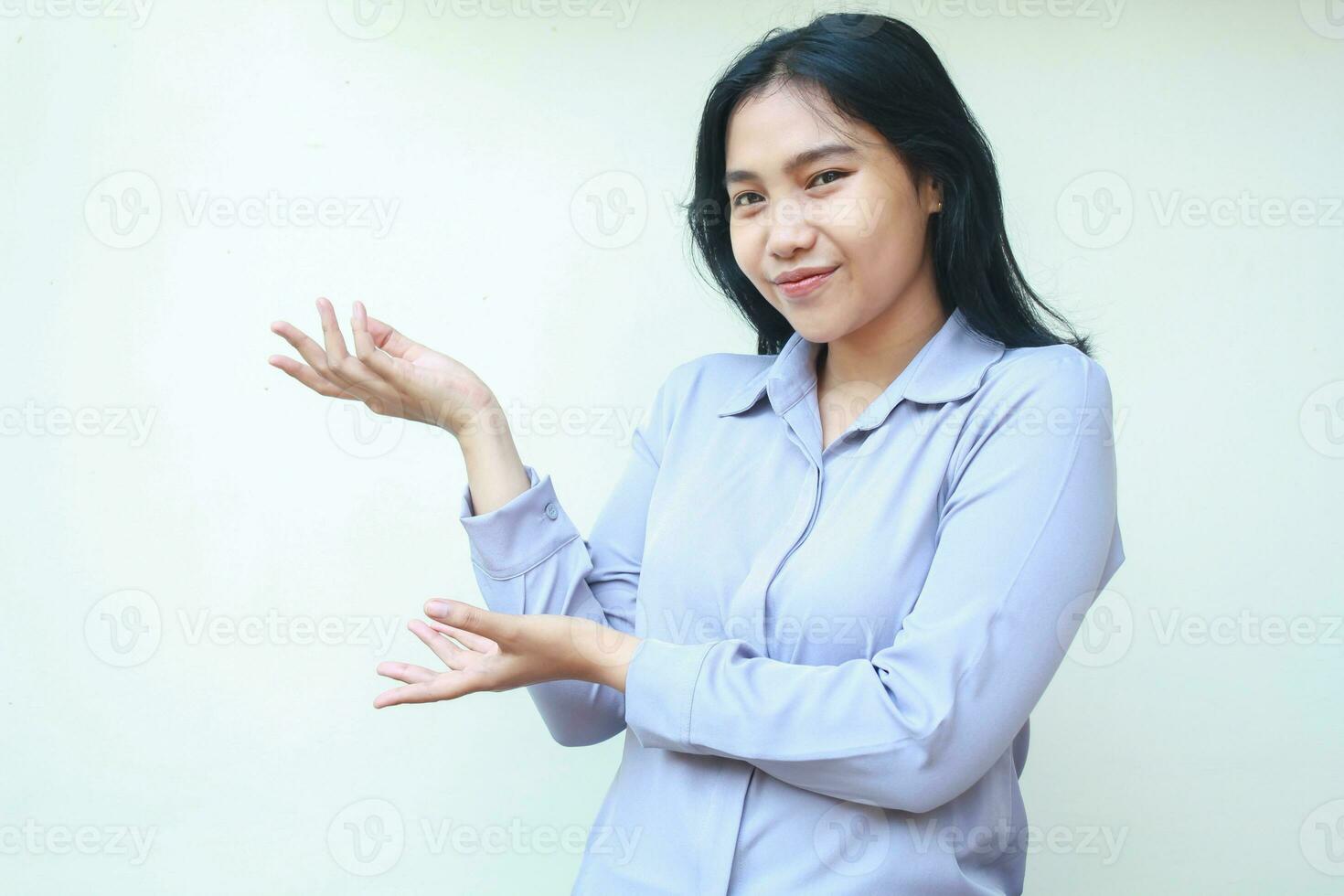 happy calm asian young business woman do presenting gesture showing open palm to empty space announce imaginary product, wear formal shirt, isolated in white background, looking at camera photo