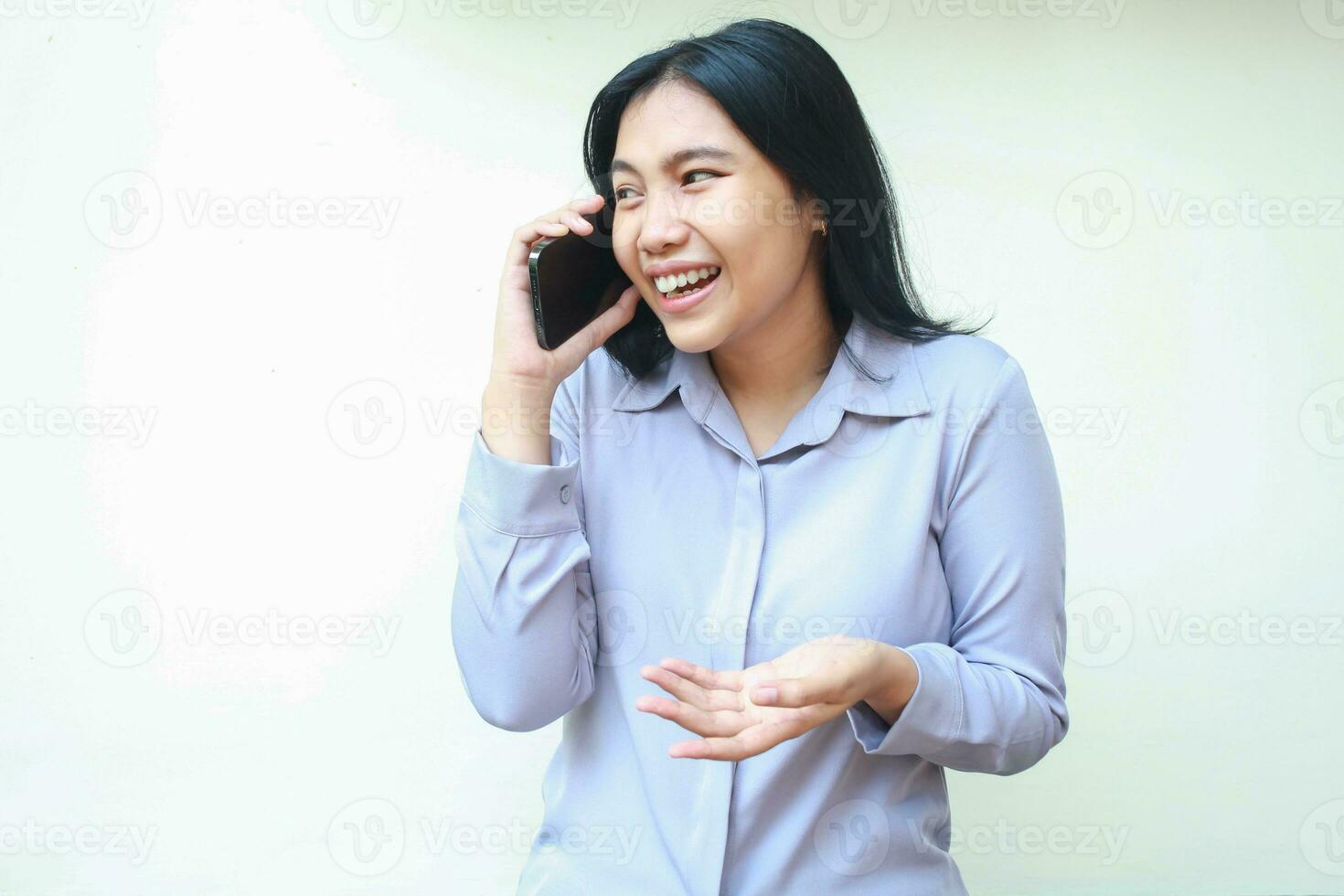 imagen de contento asiático joven negocio mujer disfrutar Hablando en moblie teléfono con alegría risa vestido en fromal púrpura camisa mirando lejos en pie terminado aislado blanco antecedentes foto