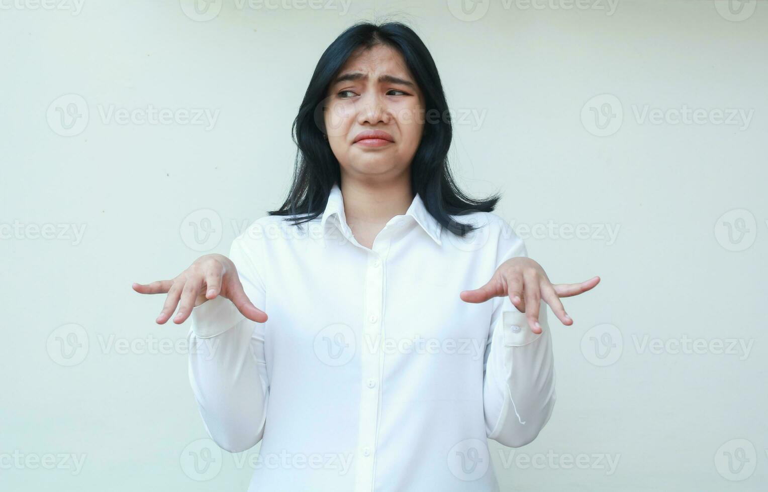 portrait of doubtful asian woman office girl wearing white formal suit shirt raising palms standing do uderestimate gesture showing do not believe expression looking away photo