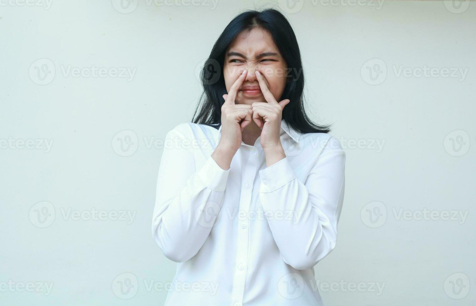 studio shot of dissappointed asian young woman executive wear formal white suit looking aside thinking about something with fingers touching her nose, standing photo