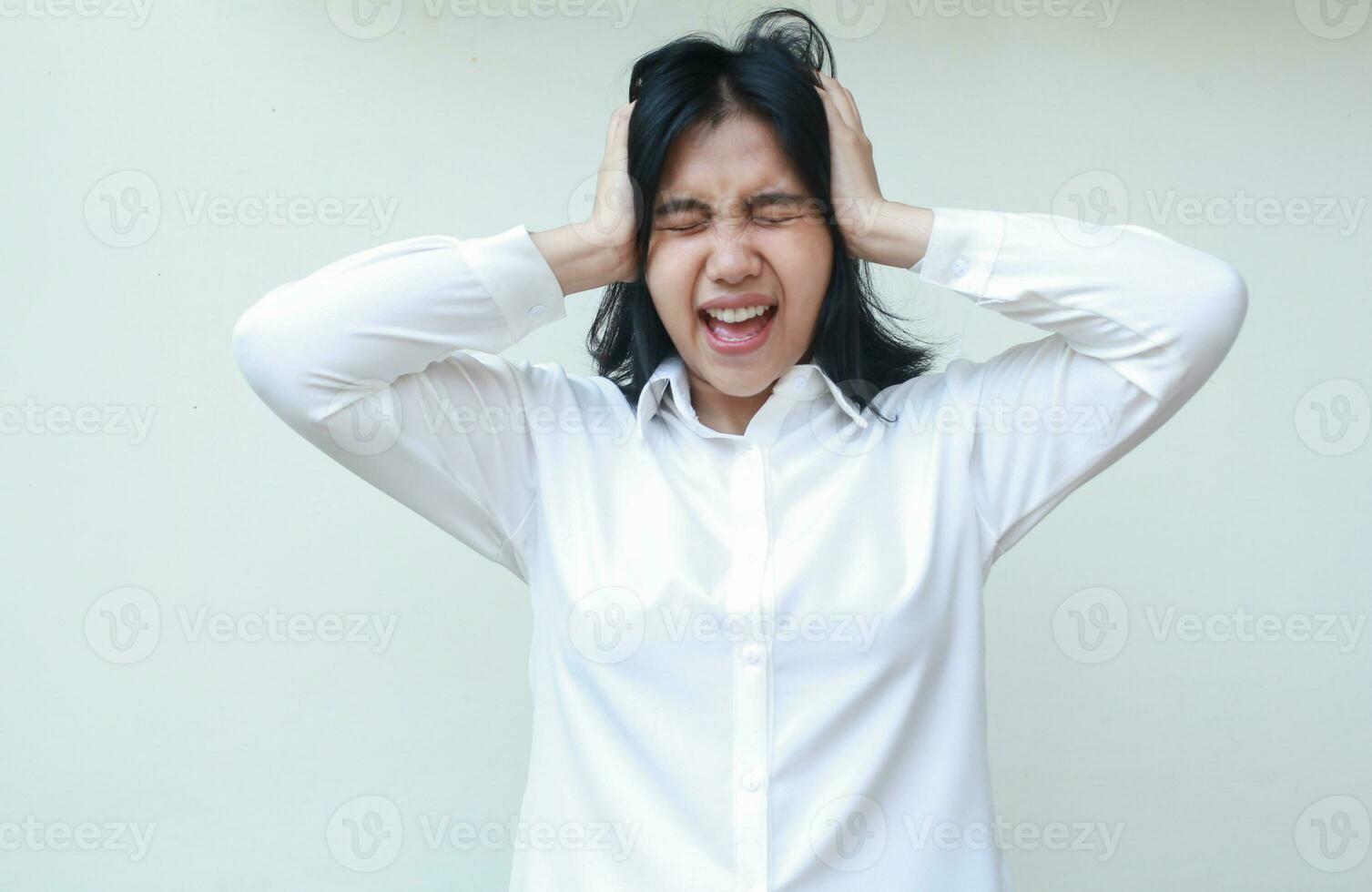 portrait of depressed asian young business woman screaming and shouting pushing her head with two palms, stressed with job deadline work pressure wearing white formal shirt, standing, mental health photo