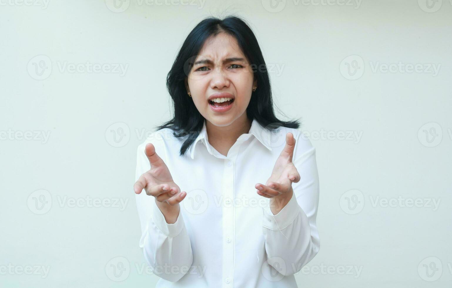 so what. furious asian business woman keep palms sideways and shrugging shoulders questioning what happen with angry frowning face wear formal white shirt standing over isolated background photo