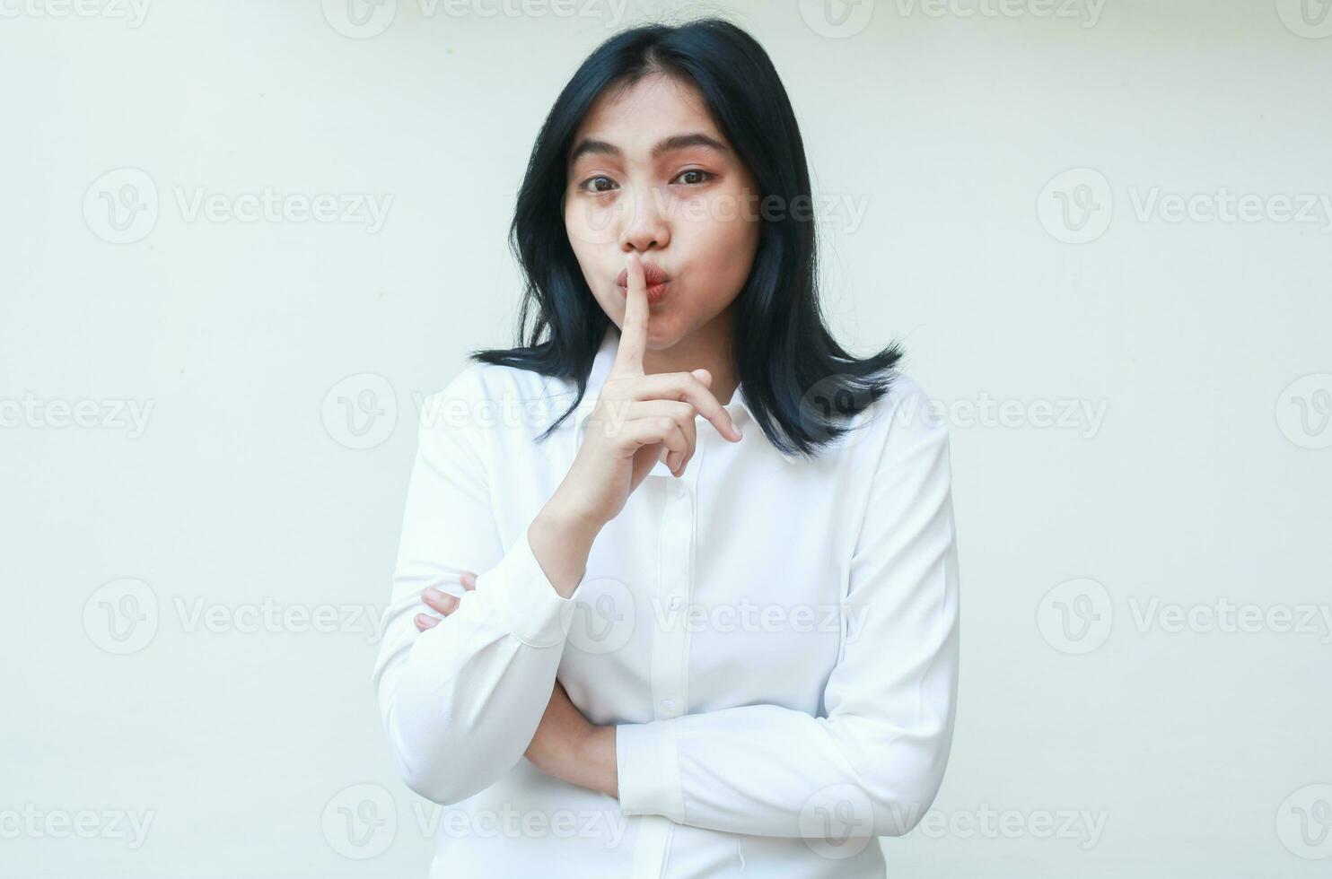 happy calm beauty young asian business woman manager looking at camera with forefinger on lips mouth show silent gesture wearing white formal suit shirt, stop noise please photo