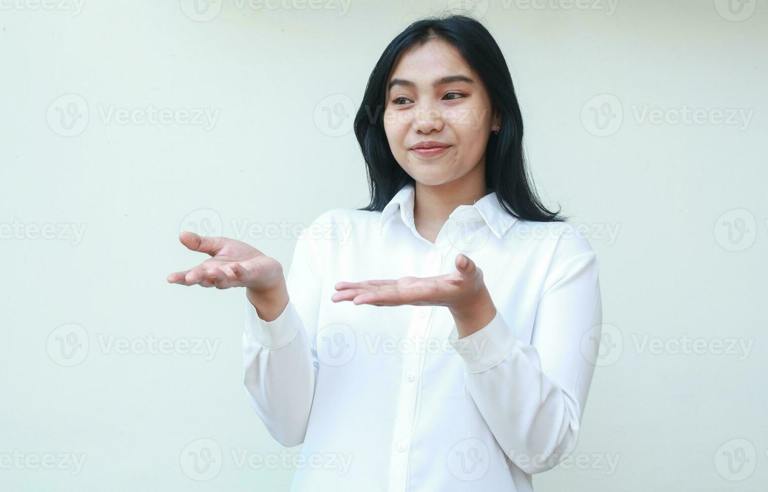 image of grateful pleased asian saleswoman manager raising open palms showing recommended product wearing white suit shirt looking away, presenting offer gesture, standing over isolated background photo