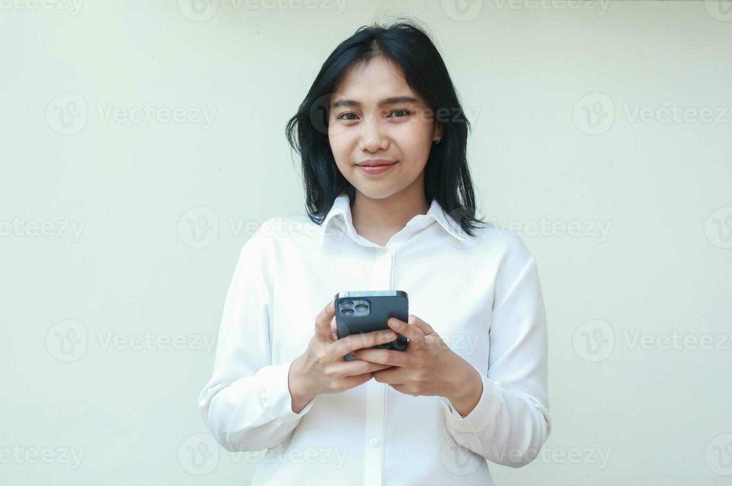 elegant pretty asian business woman surfing social media on smartphone hold on hands looking camera with grateful smile wearing white suit shirt standing over isolated background, online shopping photo