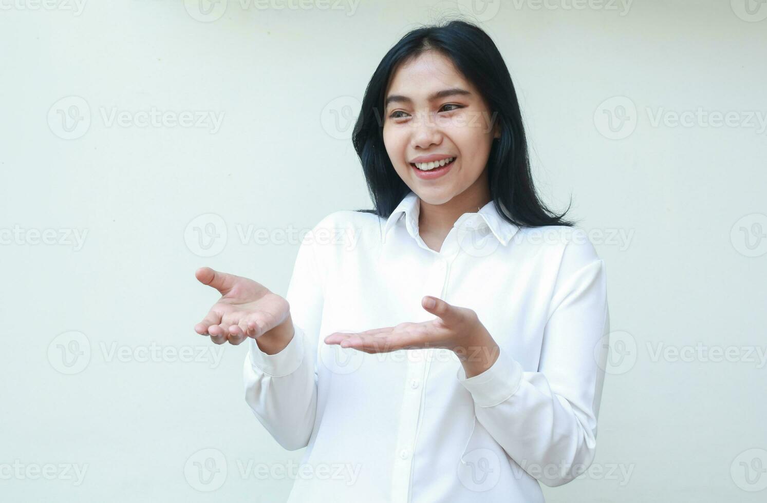smiling pleased asian business woman excited showing empty open palms wearing white formal suit shirt looking away, presenting product offer gesture, sales promotion, standing isolated background photo