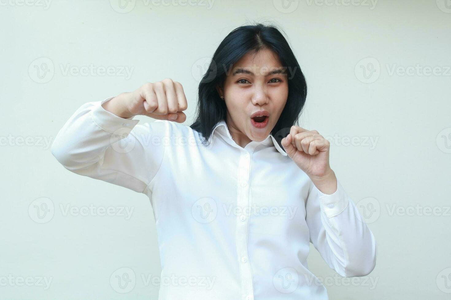 alegría asiático negocio mujer levantamiento puño demostración si gesto y lucha, gritando con Guau expresión a cámara, vistiendo blanco camisa formal traje aislado en blanco antecedentes foto