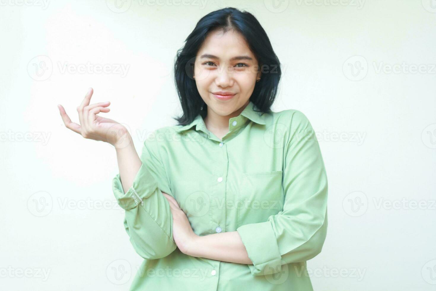content satisfied glad asian woman with dark hair raising palms to side empty space introducing product wearing green over size shirt standing isolated white background, recommend offering gesture photo