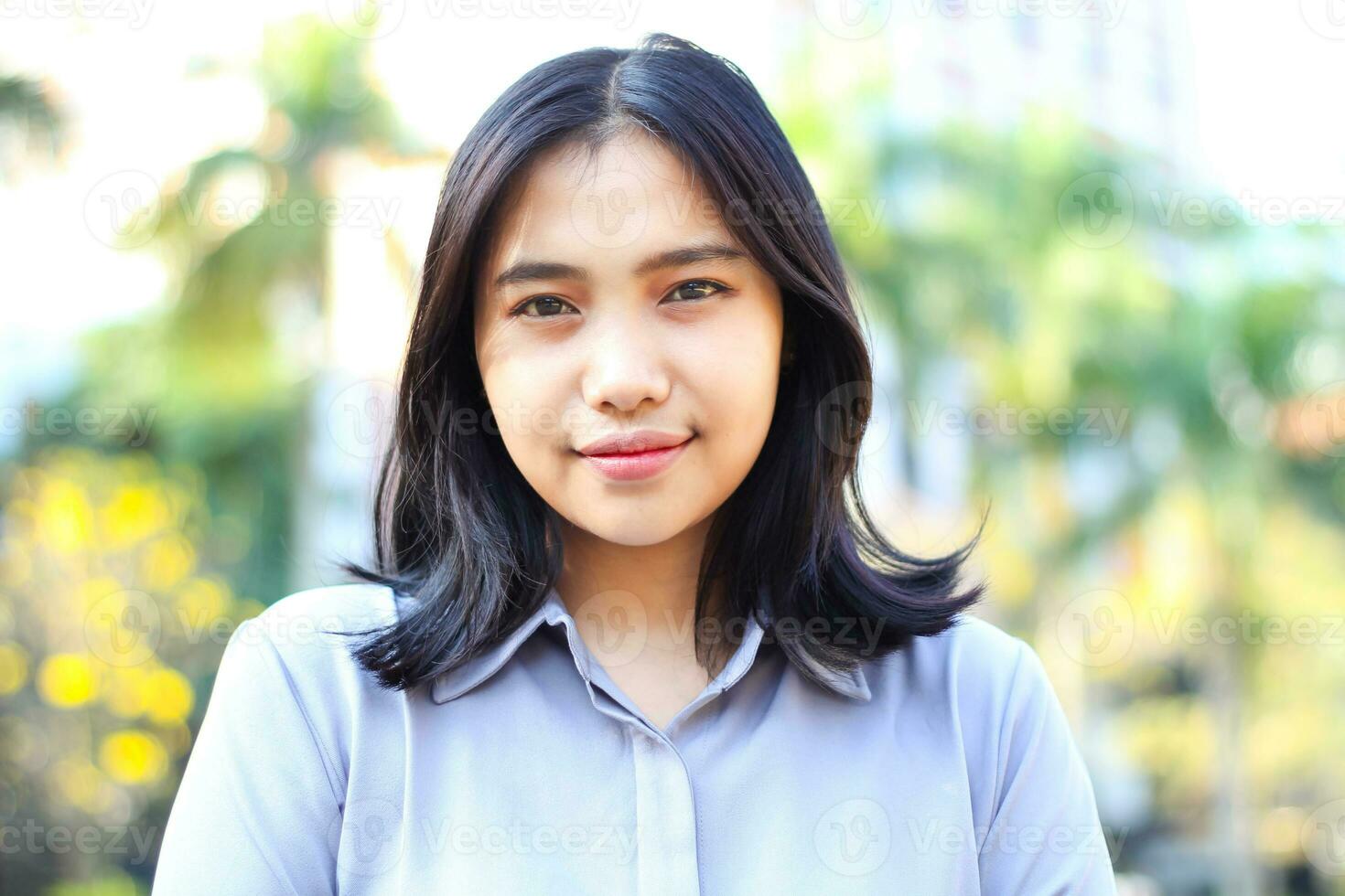 close up asian business woman smiling at camera wearing formal suit standing over city building and green plant background photo