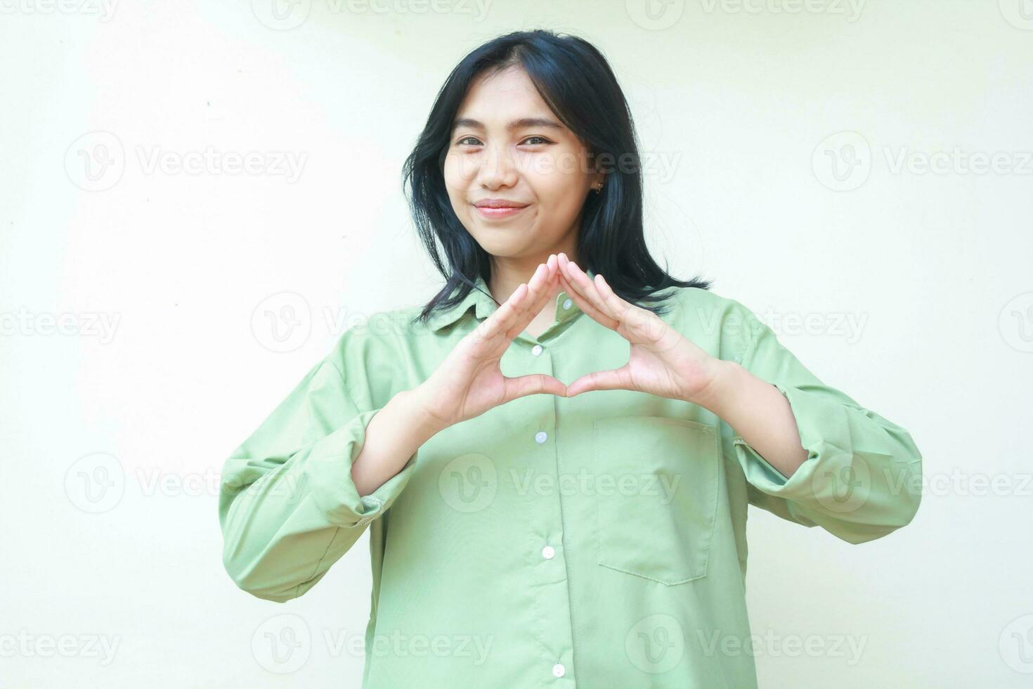 happy asian woman with dark hair wearing green over size shirt showing triangle shape symbols over chest standing isolated white background photo