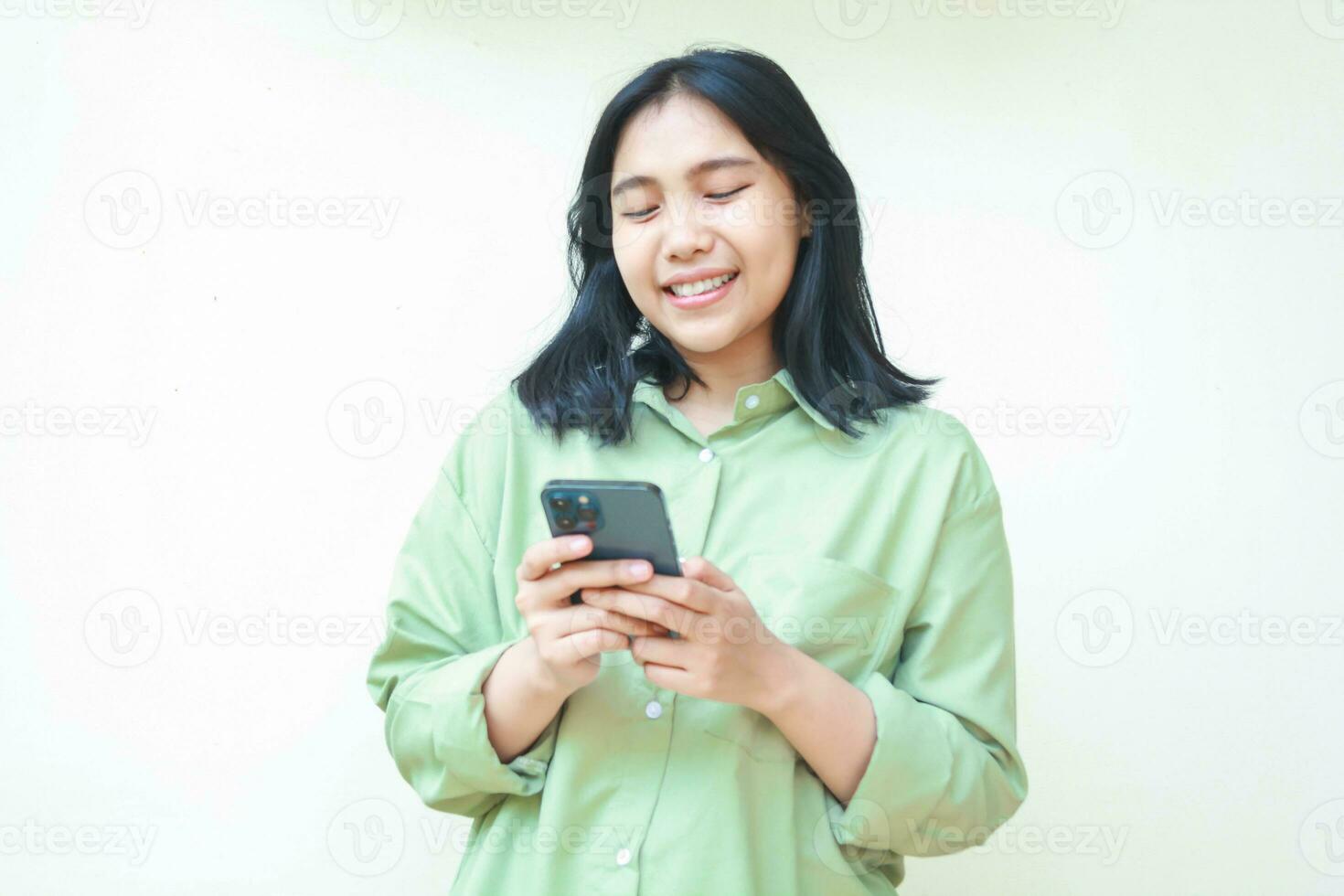happy asian woman wearing green casual shirt smiling while using smartphone apps and social media isolated on white background photo