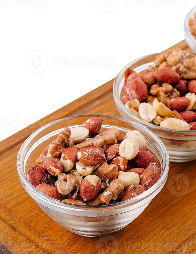 Assorted nuts in a glass bowls on wooden photo