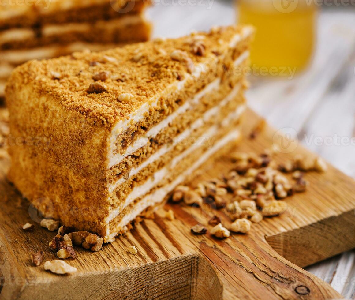 Slice of sweet honey cake on wooden board photo