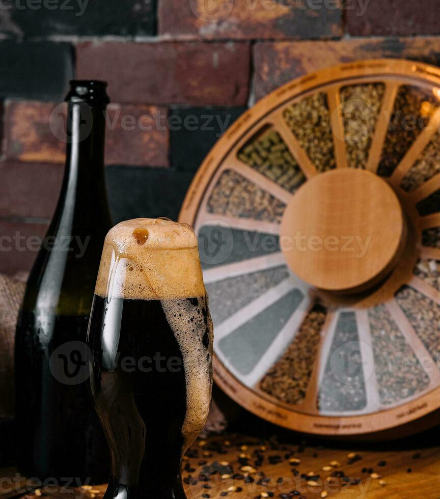 Glass of dark beer and bottle on wooden photo