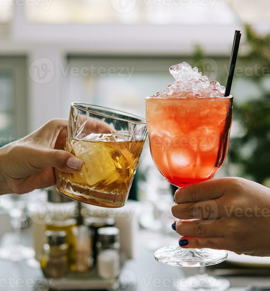 Friends toasting with glasses of whiskey and strawberry cocktail photo
