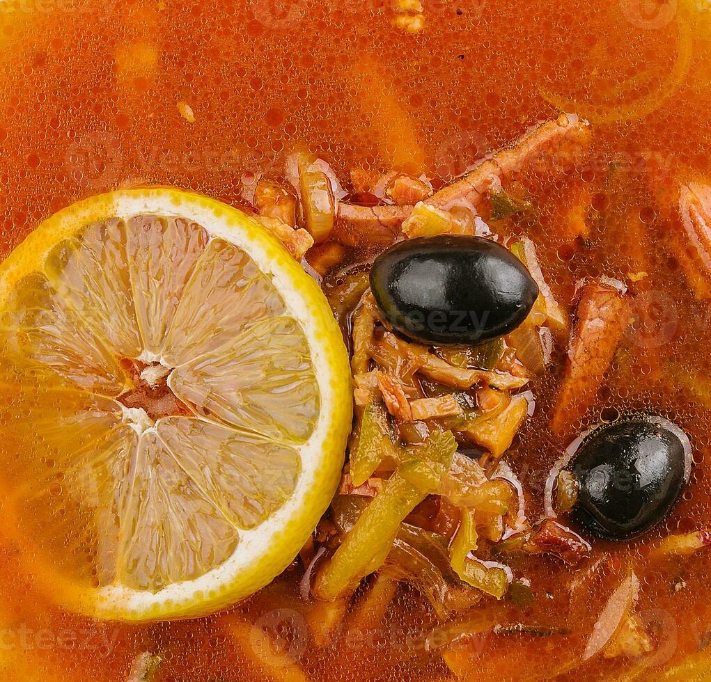 Solyanka mix soup with sausages, olives and lemon photo