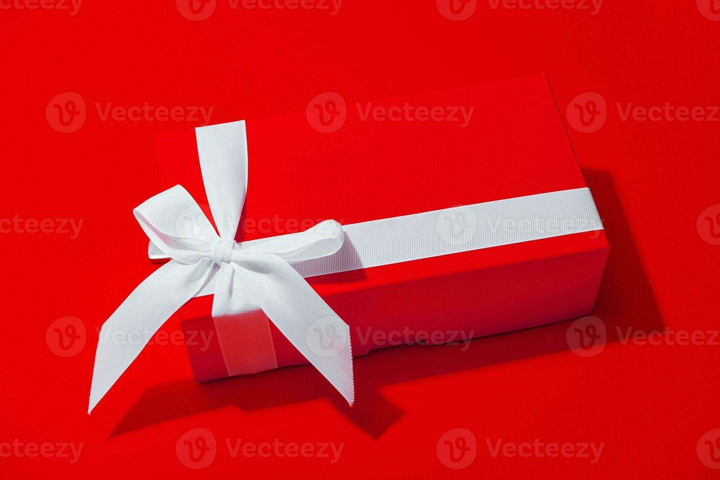 Red gift box with white ribbon isolated on yellow photo