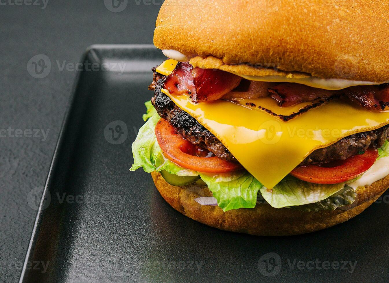 Bacon burger with beef patty on black tray photo