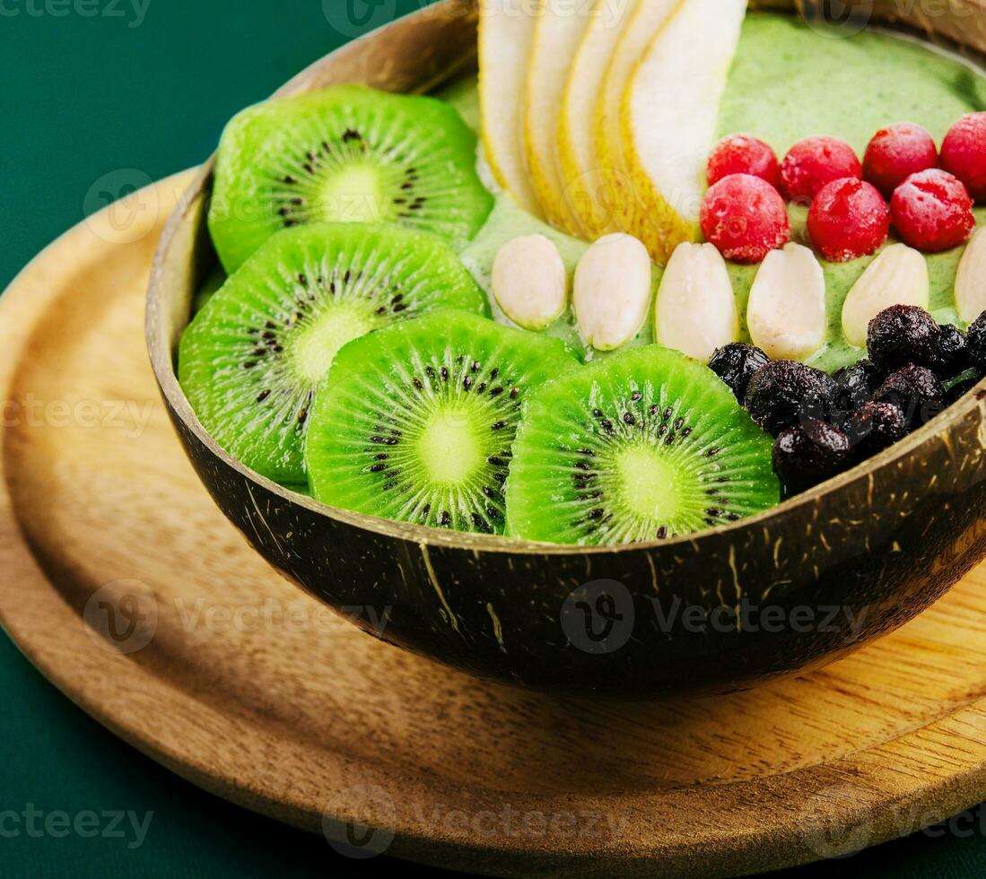 Green smoothie bowl with nuts, kiwi, pear, berry and granola photo