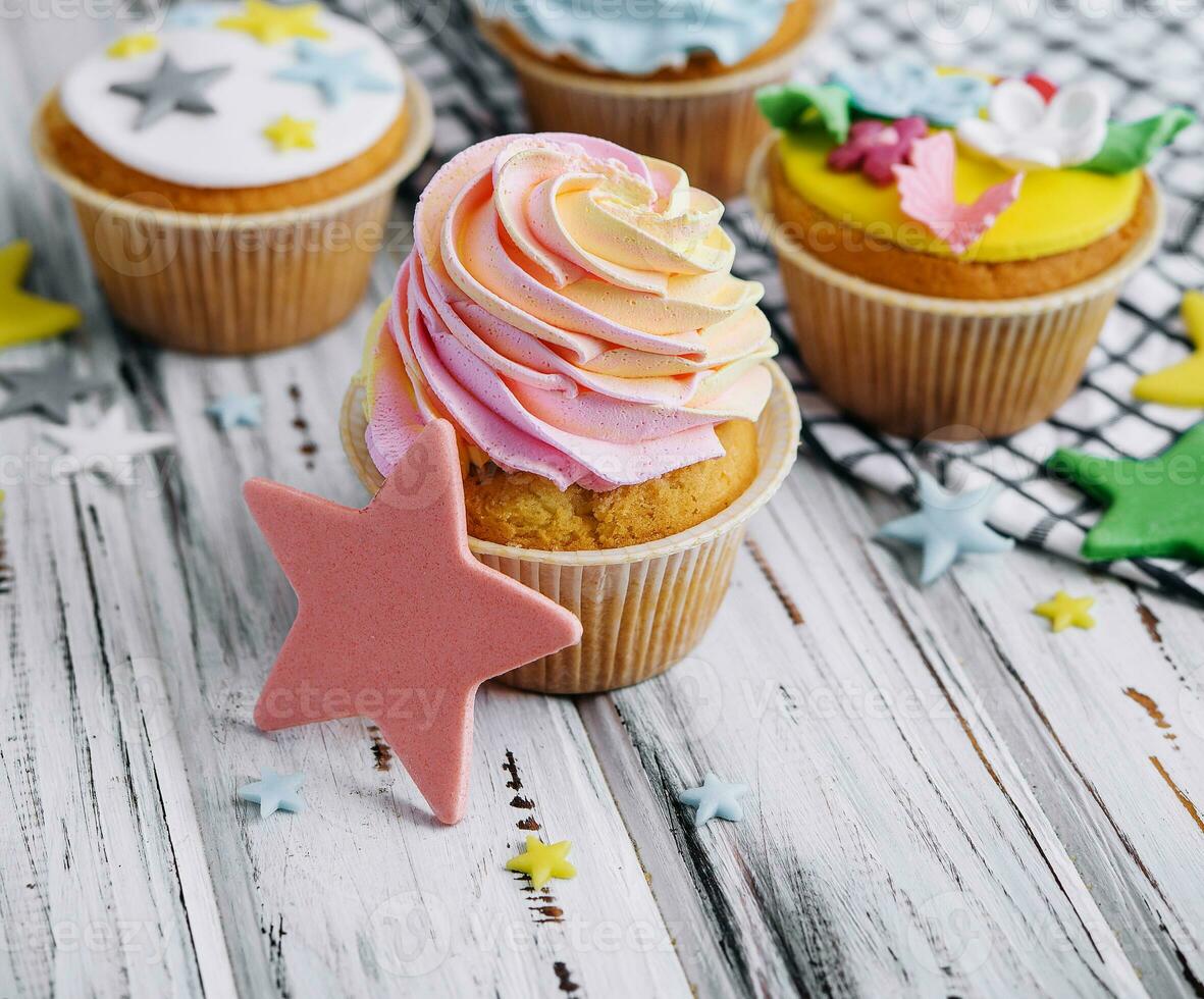 Multiple colorful nicely decorated muffins on a wooden background photo