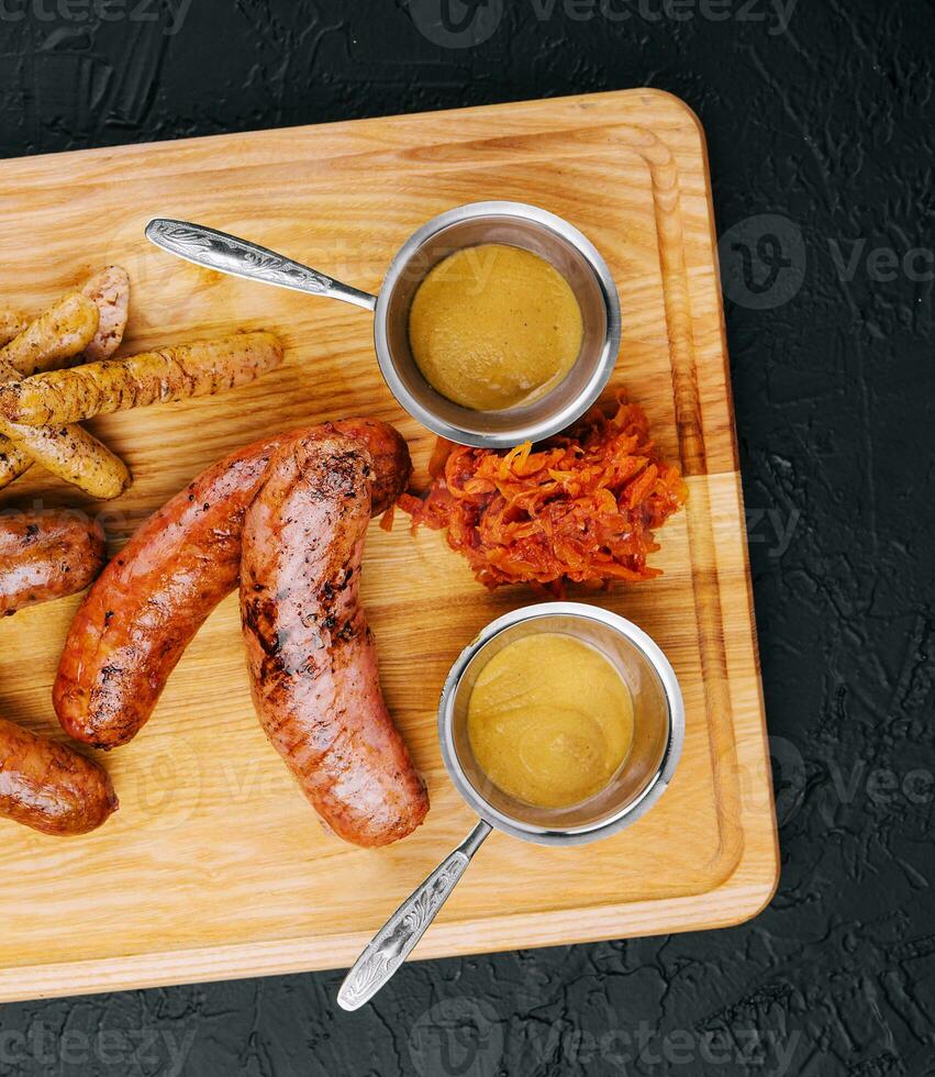 Delicious fresh grilled sausages on wooden table photo
