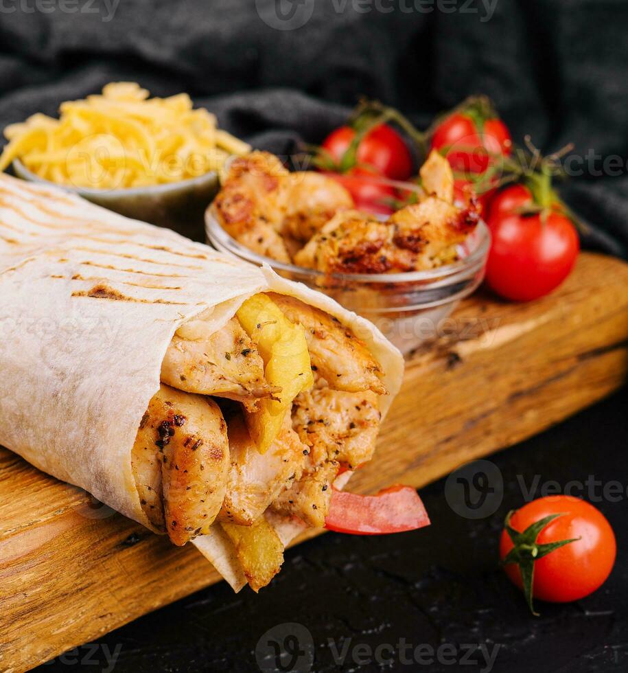 Delicious shawarma on a wooden board on a dark wooden table photo