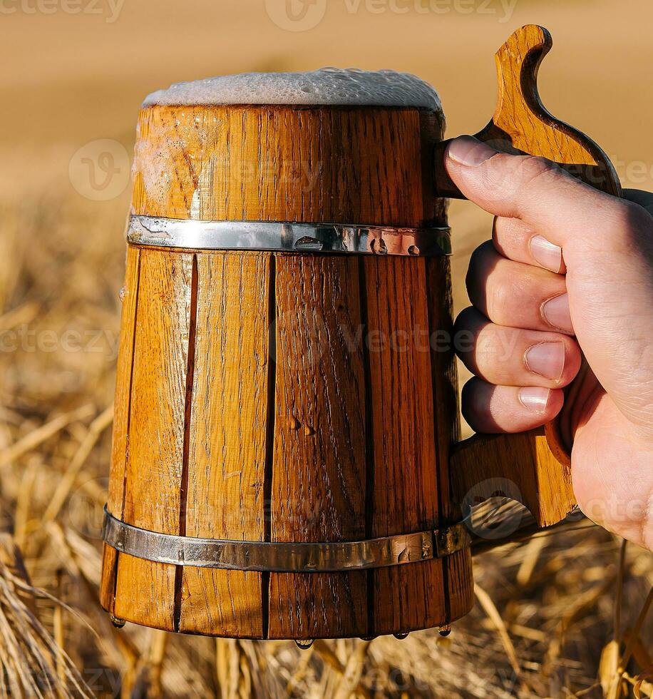 hand holding a wooden mug with beer photo