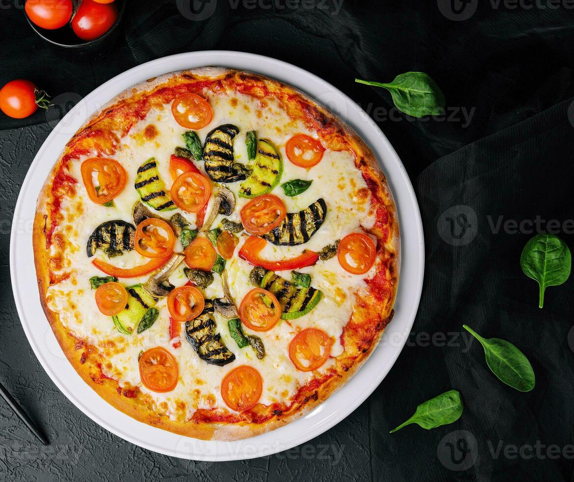 vegetarian pizza with zucchini, eggplant, mushrooms and tomato photo