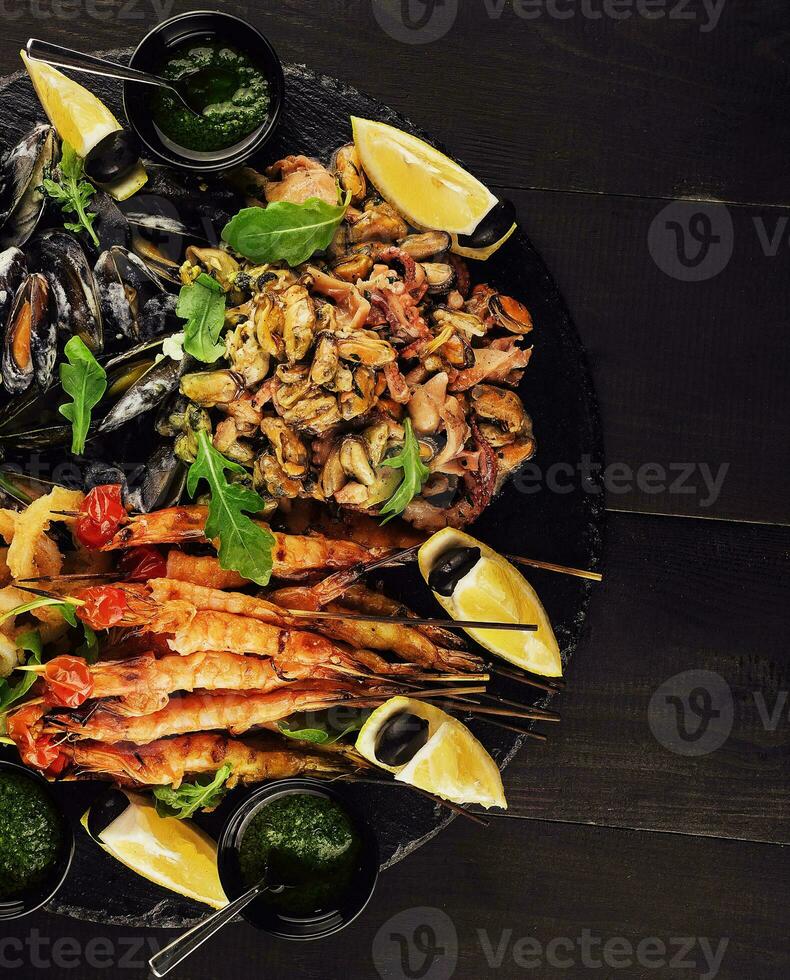 fried shrimp, squid rings, mussels, octopus and pesto sauce photo