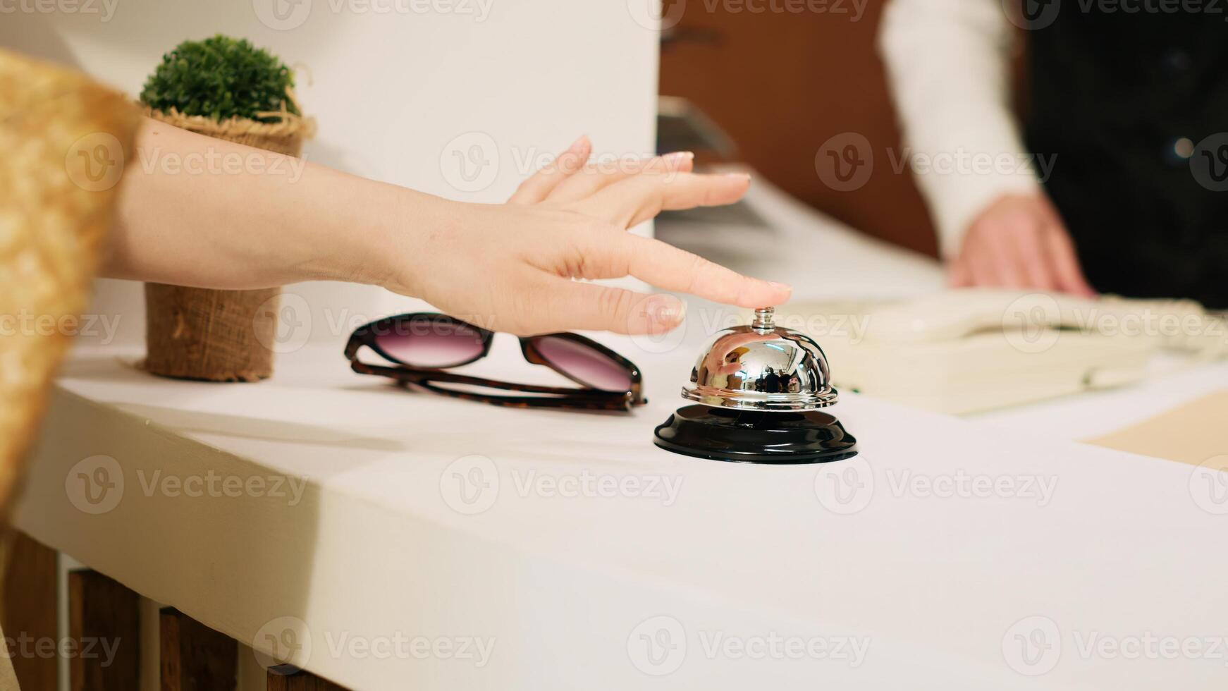 Impatient guest ringing service bell at counter, asking for assistance from front desk staff in hotel. Tourist at tropical resort waiting for check in, summertime vacation. Handheld shot. Close up. photo