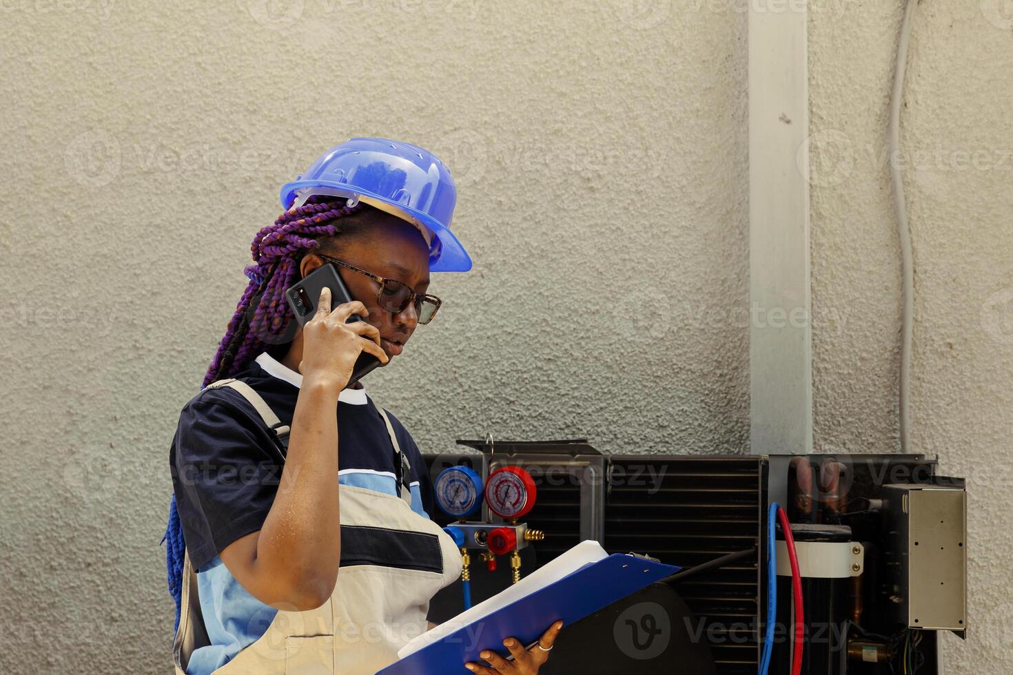 African american apprentice informing master technician over the phone about air conditioner parts needing to be replaced. Mechanic checking maintenance plan after finishing air filters cleaning photo