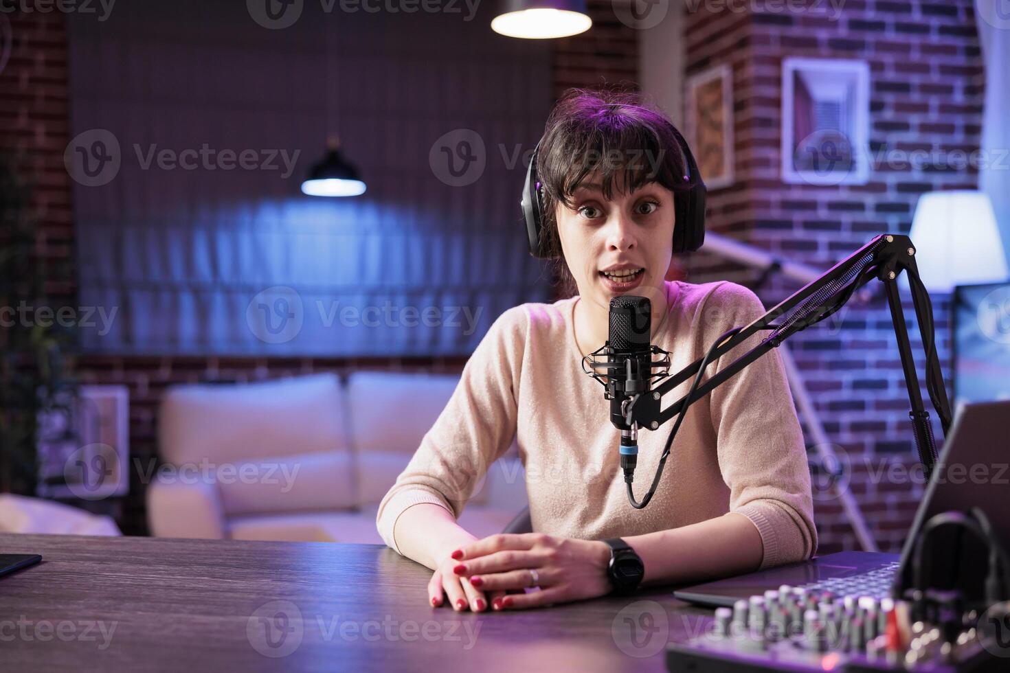 Portrait of happy social media star filming live show from her home studio, talking to internet channel audience. Content creator recording vlogging episode using professional camera photo