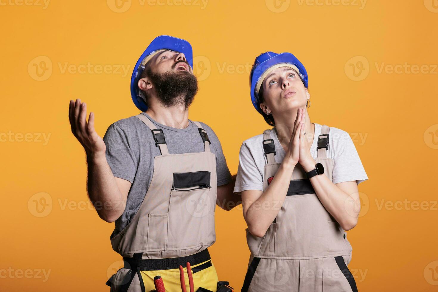 Faithful construction workers praying to god for good projects, begging for help. Team of engineering experts holding prayer hands to ask for fortune and luck, wearing overalls and helmets. photo