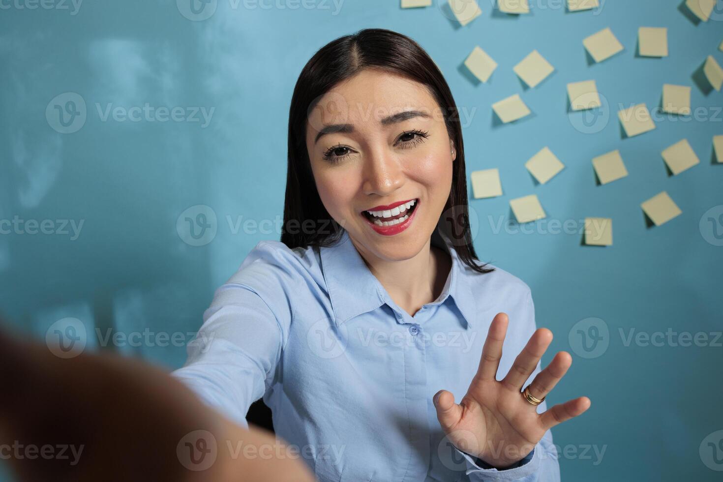 Businesswoman on video call with mobile phone talking in a friendly way with friends during break time. Female office employee using mobile device for remote communication. photo