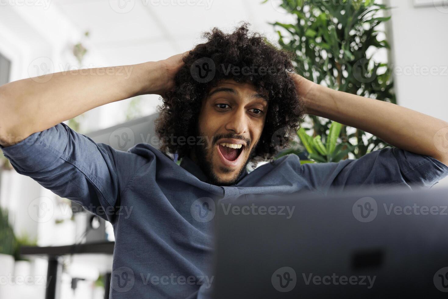 Arab start up company entrepreneur shocked with high sales growth while checking results on laptop. Executive manager celebrating effective marketing strategy in business office photo