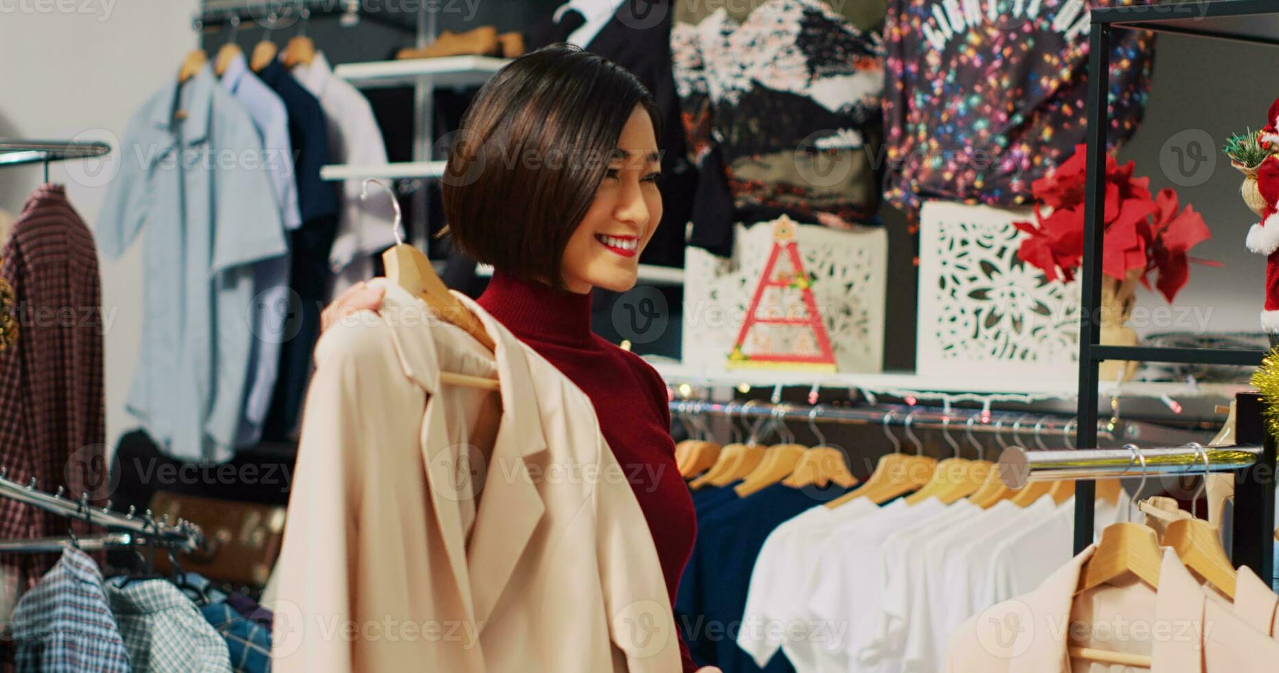 Woman browsing through elegant blazers on racks in Christmas decorated shopping store, looking for perfect xmas dinner attire. Fashionable customer in need of new clothes photo