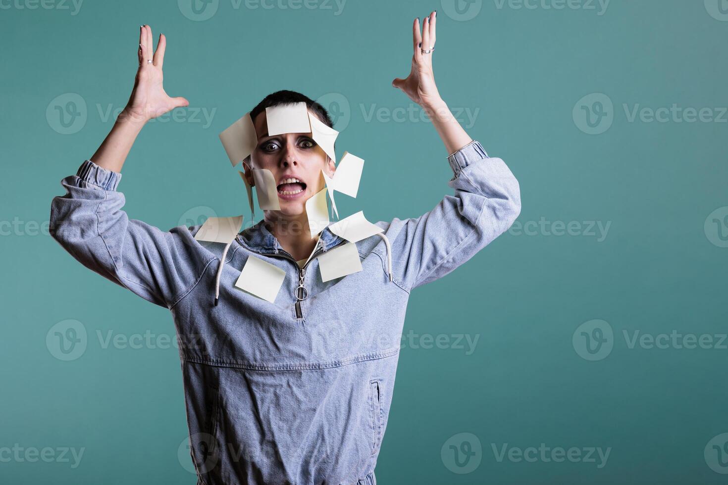 Portrait of frustrated unhappy businessperson overwhelmed of work with sticky notes on her while standing over isolated background in studio. Colorful memory reminder on exhausted depressed employee photo