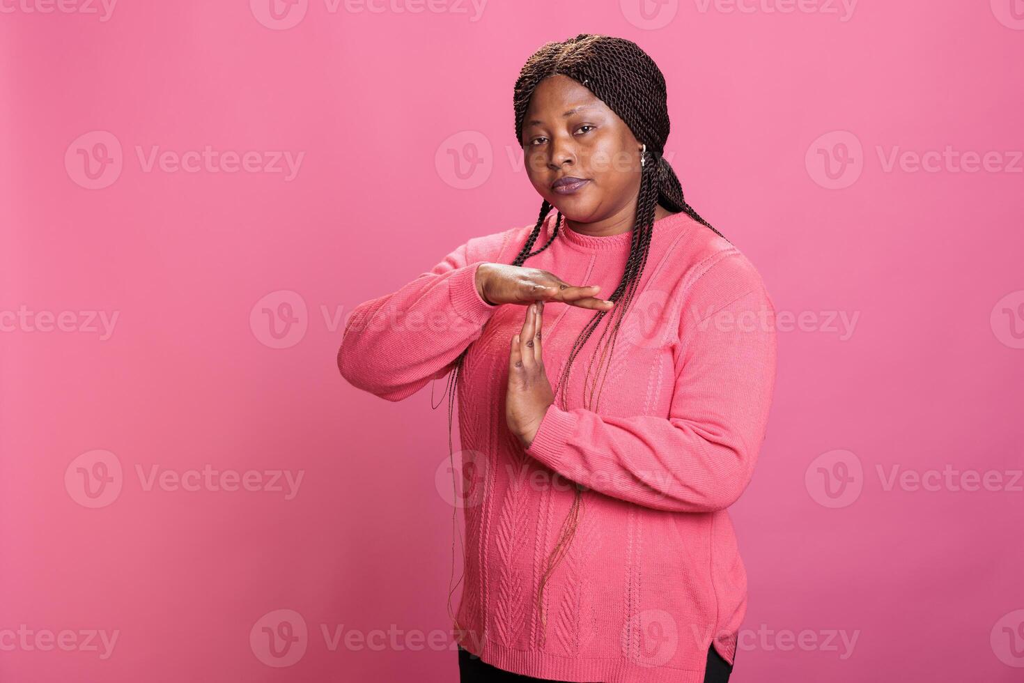 Displeased angry woman doing timeout and break gesture while making disapproval expression in studio, expressing t shape sign with hands. Serious young adult advertising refuse in studio photo