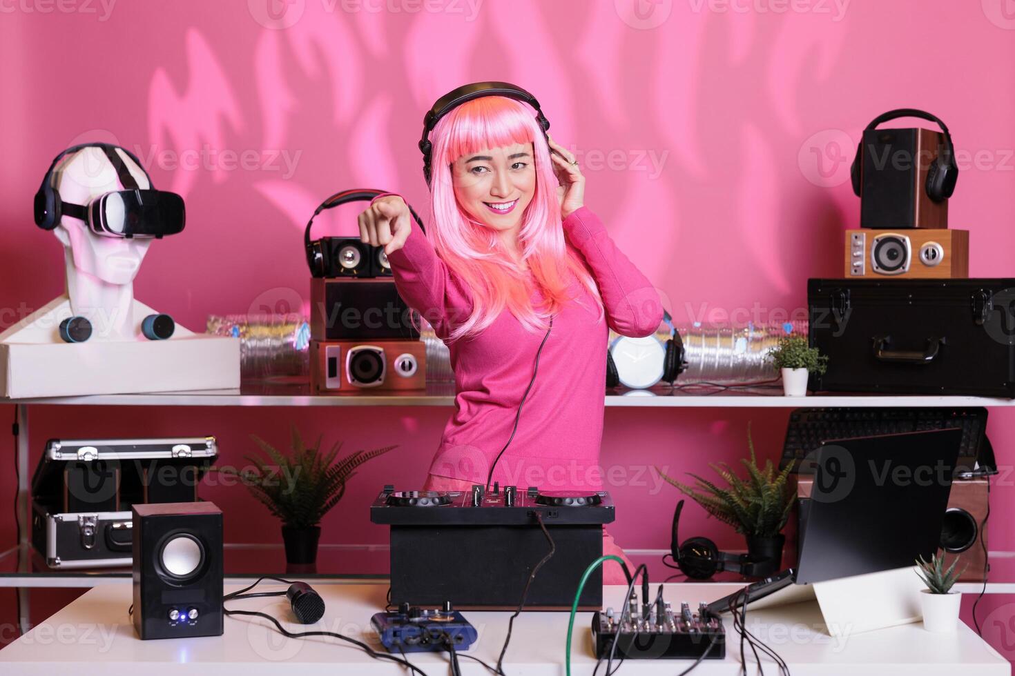 Asian musician performing electronic music using dj mixer console enjoying to play song with fans, having fun in club at night. Artist doing performance with professional audio equipment photo