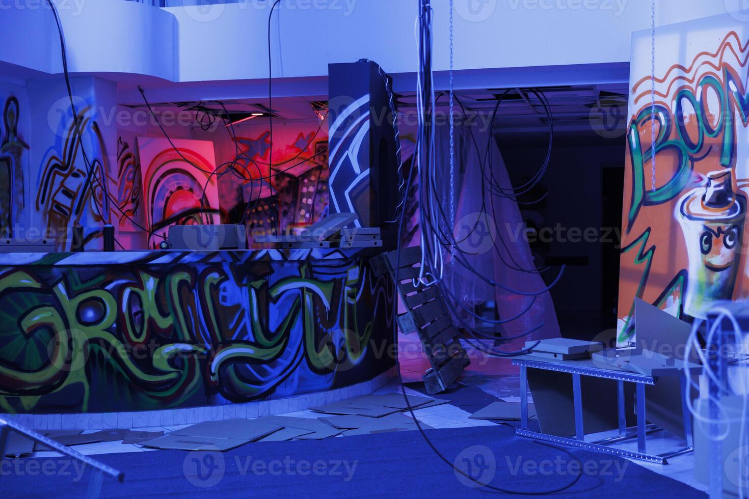 Deserted building with graffiti on walls and neon lights, empty artistic space looking grungy in purple and pink. Abandoned space glowing bright in darkness of chaos and disintegration. photo